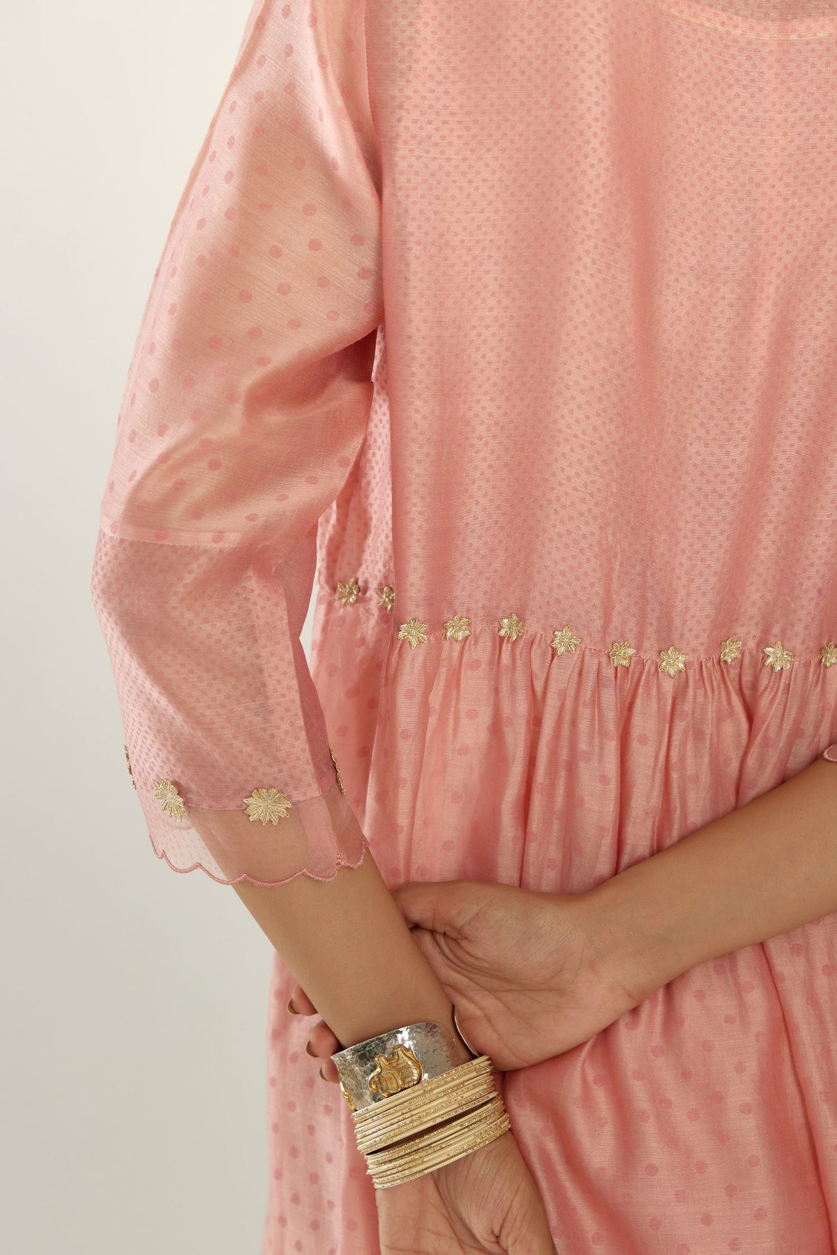 Pink hand block printed V neck gathered kurta set, highlighted with gota flower embroidery and scalloped organza at edges.