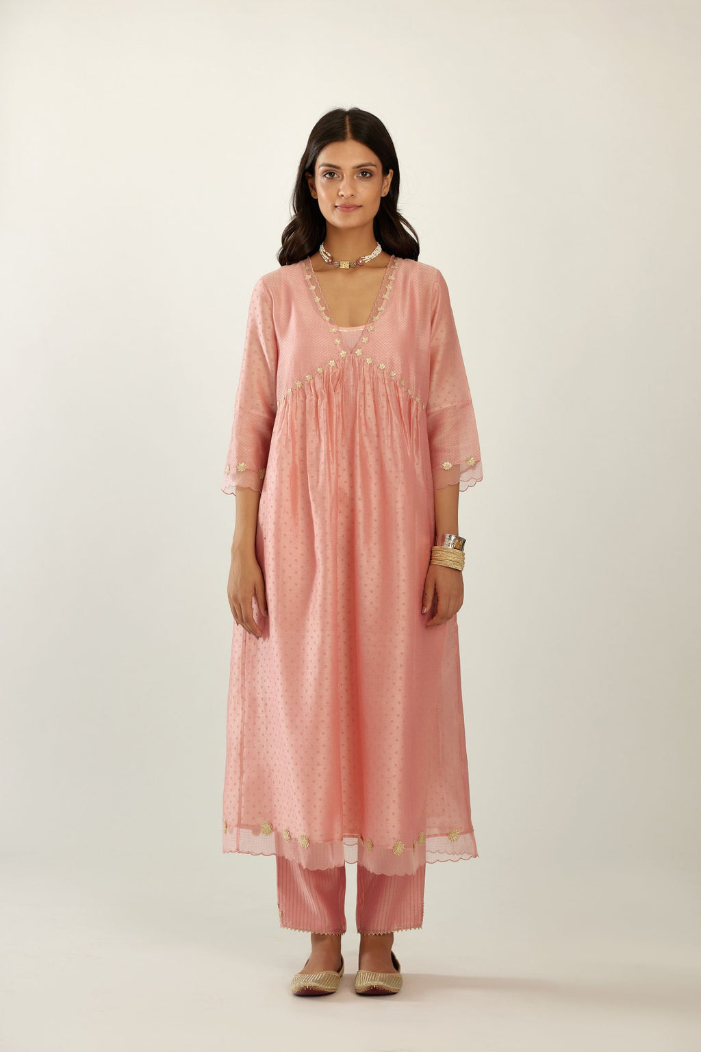 Pink hand block printed V neck gathered kurta set, highlighted with gota flower embroidery and scalloped organza at edges.