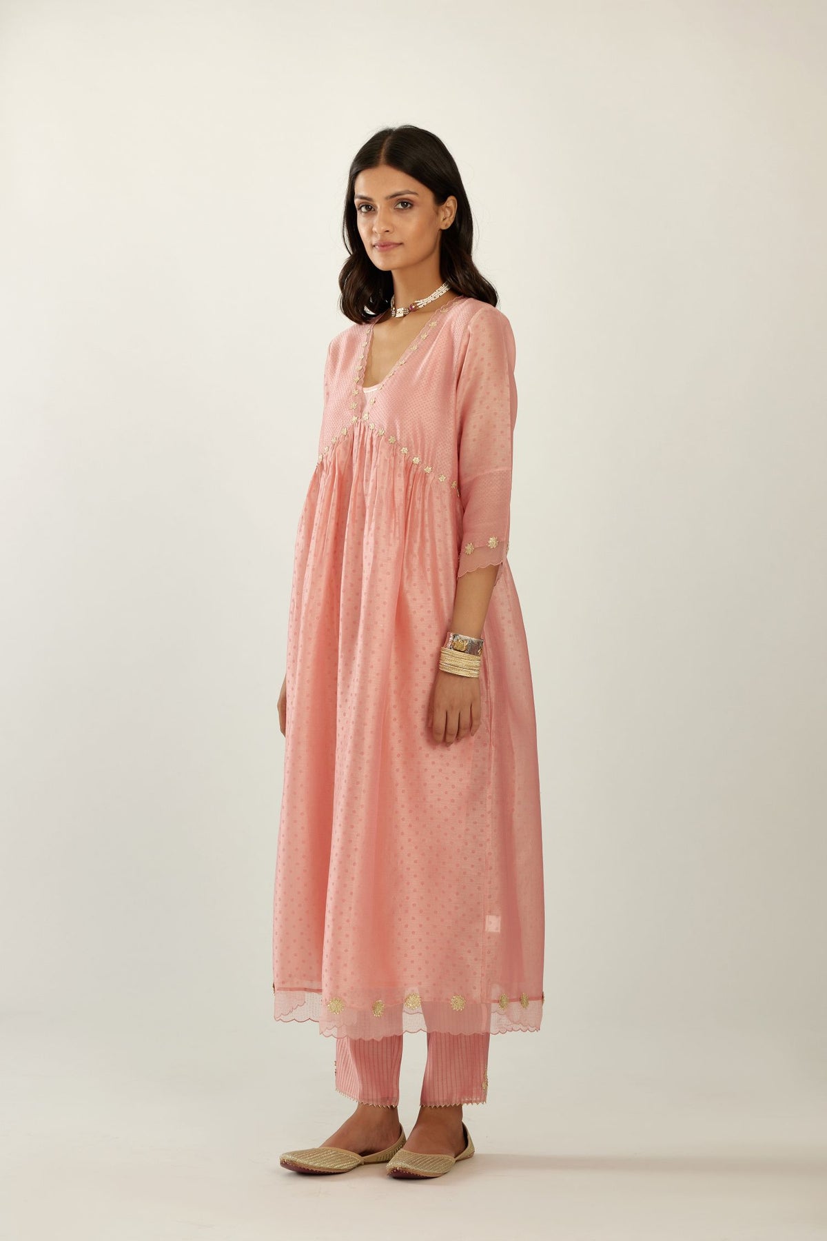 Pink hand block printed V neck gathered kurta set, highlighted with gota flower embroidery and scalloped organza at edges.