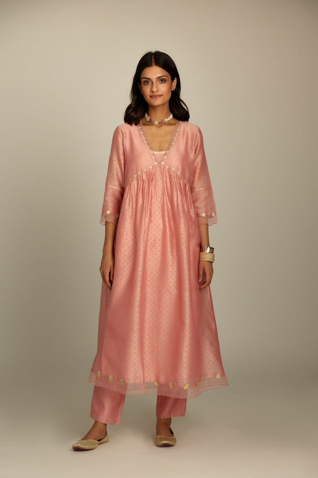 Pink hand block printed V neck gathered kurta set, highlighted with gota flower embroidery and scalloped organza at edges.