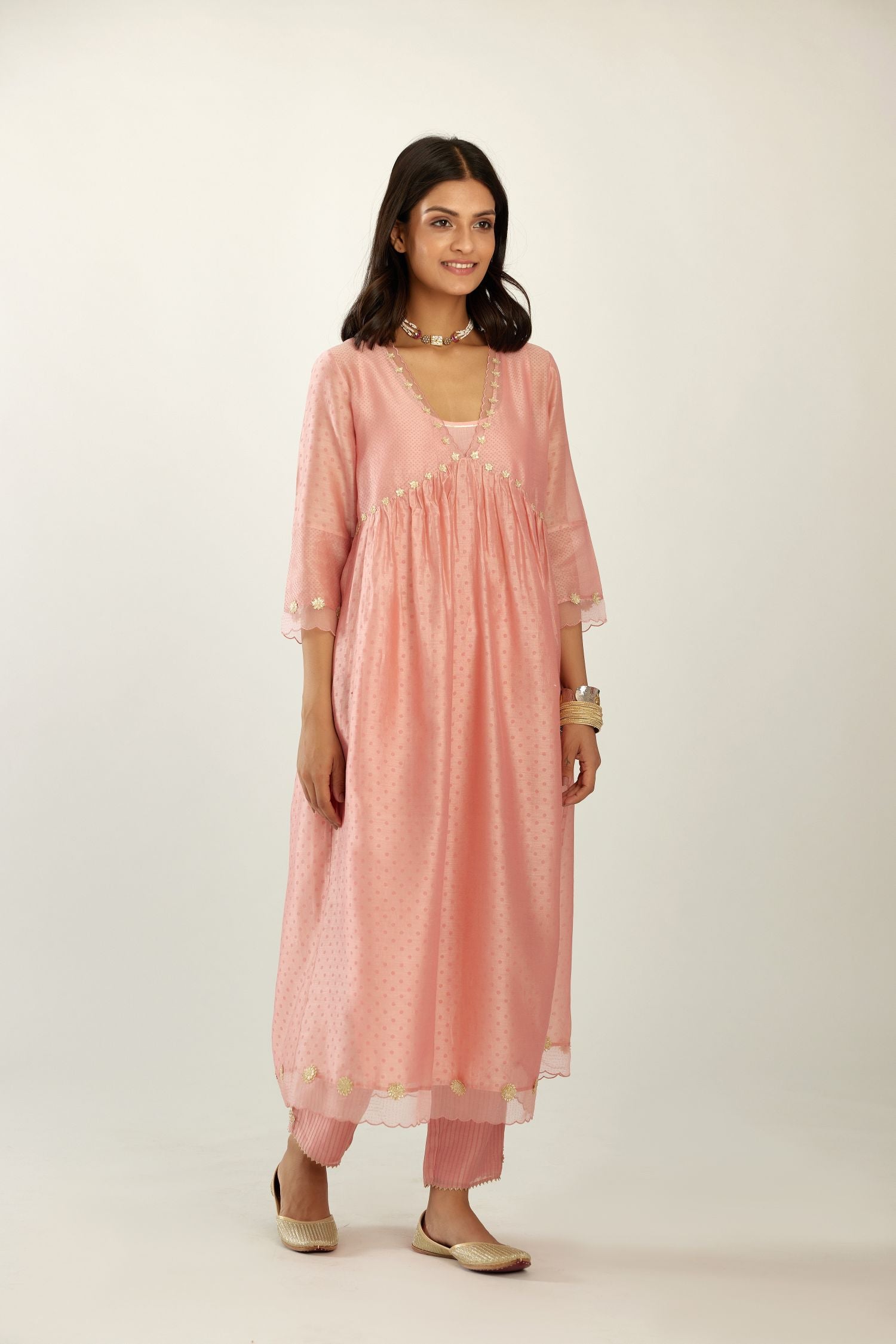 Pink hand block printed V neck gathered kurta set, highlighted with gota flower embroidery and scalloped organza at edges.
