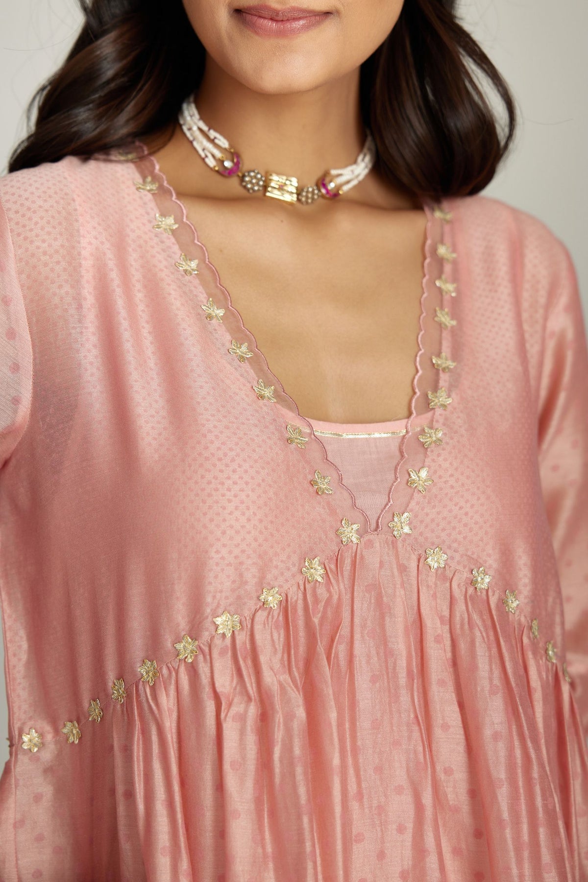 Pink hand block printed V neck gathered kurta set, highlighted with gota flower embroidery and scalloped organza at edges.