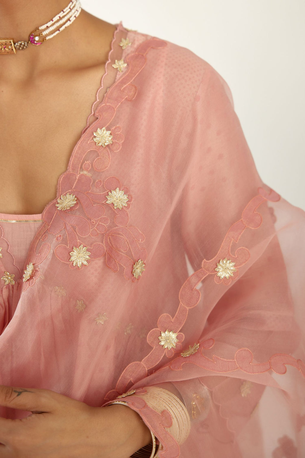 Pink hand block printed V neck gathered kurta set, highlighted with gota flower embroidery and scalloped organza at edges.