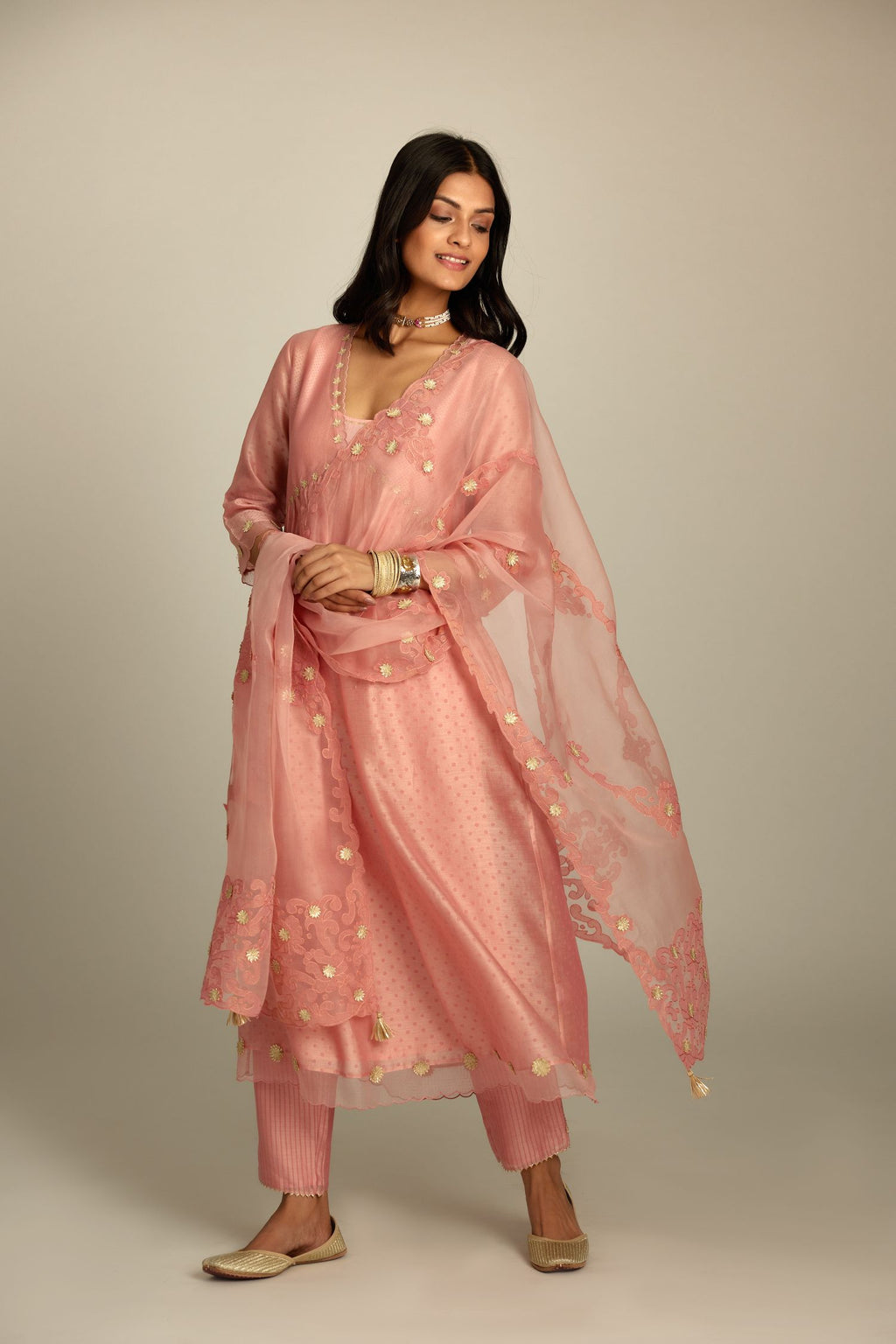 Pink hand block printed V neck gathered kurta set, highlighted with gota flower embroidery and scalloped organza at edges.