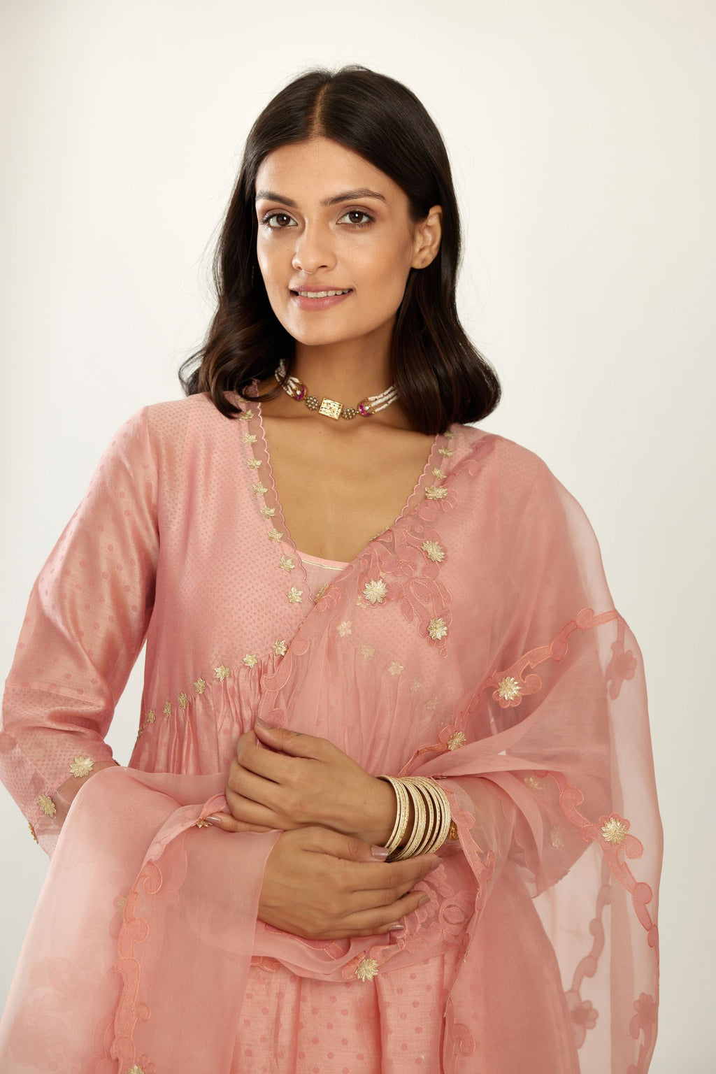 Pink hand block printed V neck gathered kurta set, highlighted with gota flower embroidery and scalloped organza at edges.