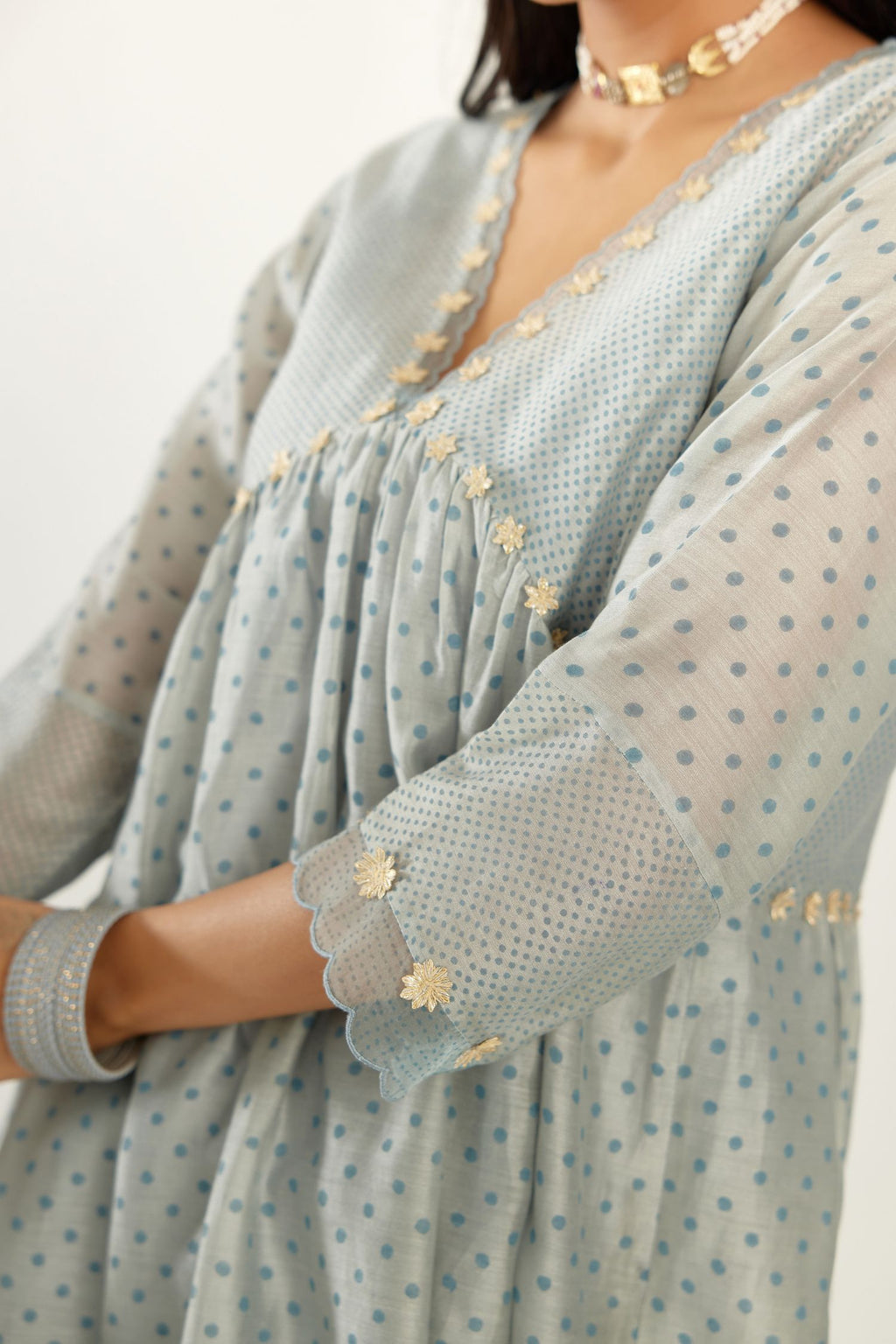 Blue hand block printed V neck gathered kurta set, highlighted with gota flower embroidery and scalloped organza at edges.