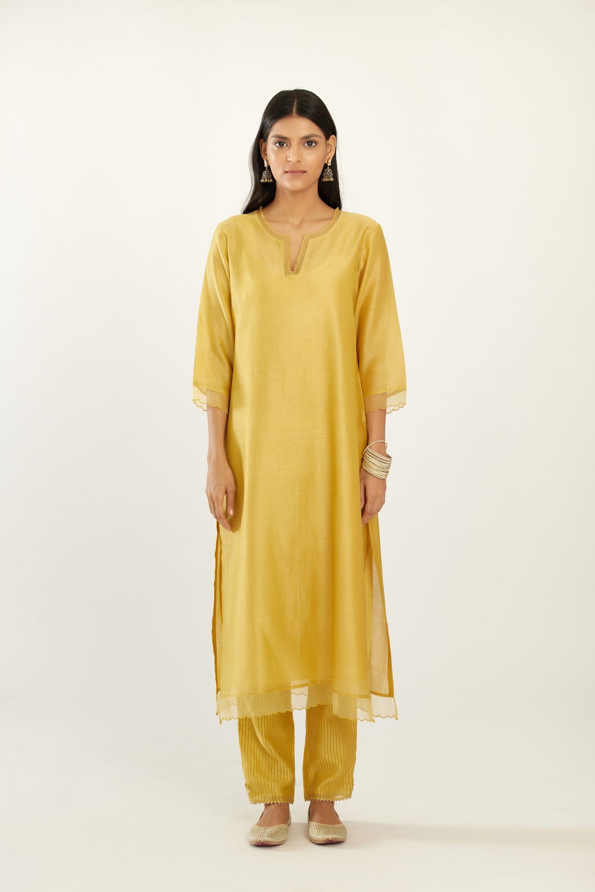 Yellow silk chanderi hand block printed straight kurta set, highlighted with scalloped organza at edges.