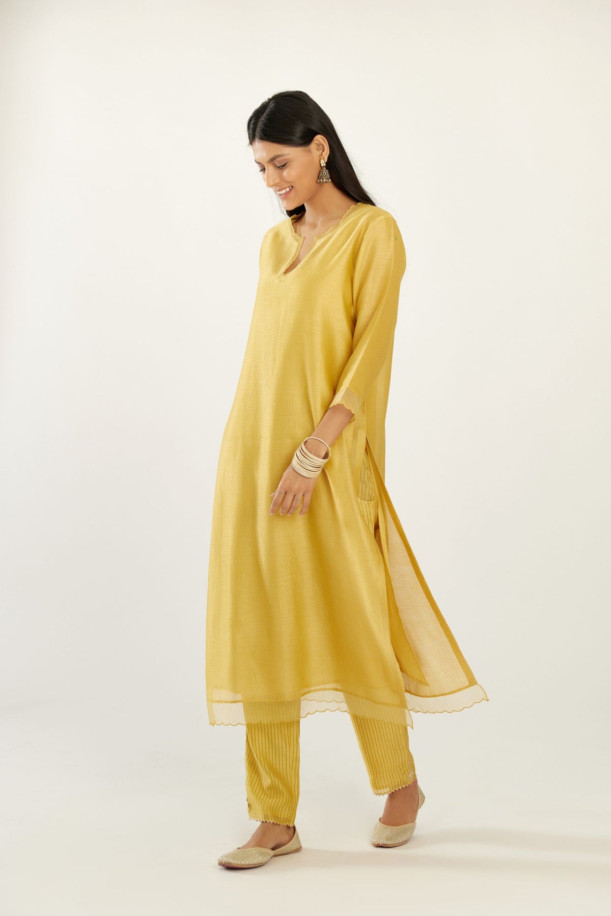 Yellow silk chanderi hand block printed straight kurta set, highlighted with scalloped organza at edges.