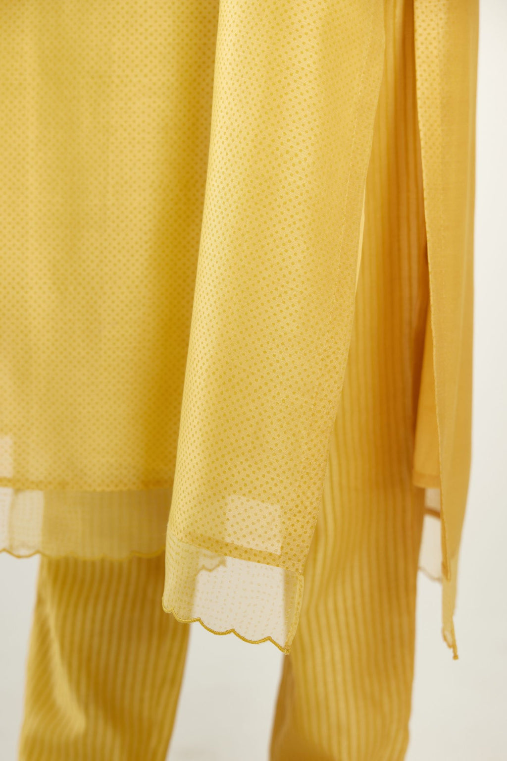 Yellow silk chanderi hand block printed straight kurta set, highlighted with scalloped organza at edges.