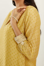 Yellow silk chanderi hand block printed straight kurta set, highlighted with organza and gota embroidered flower at edges.