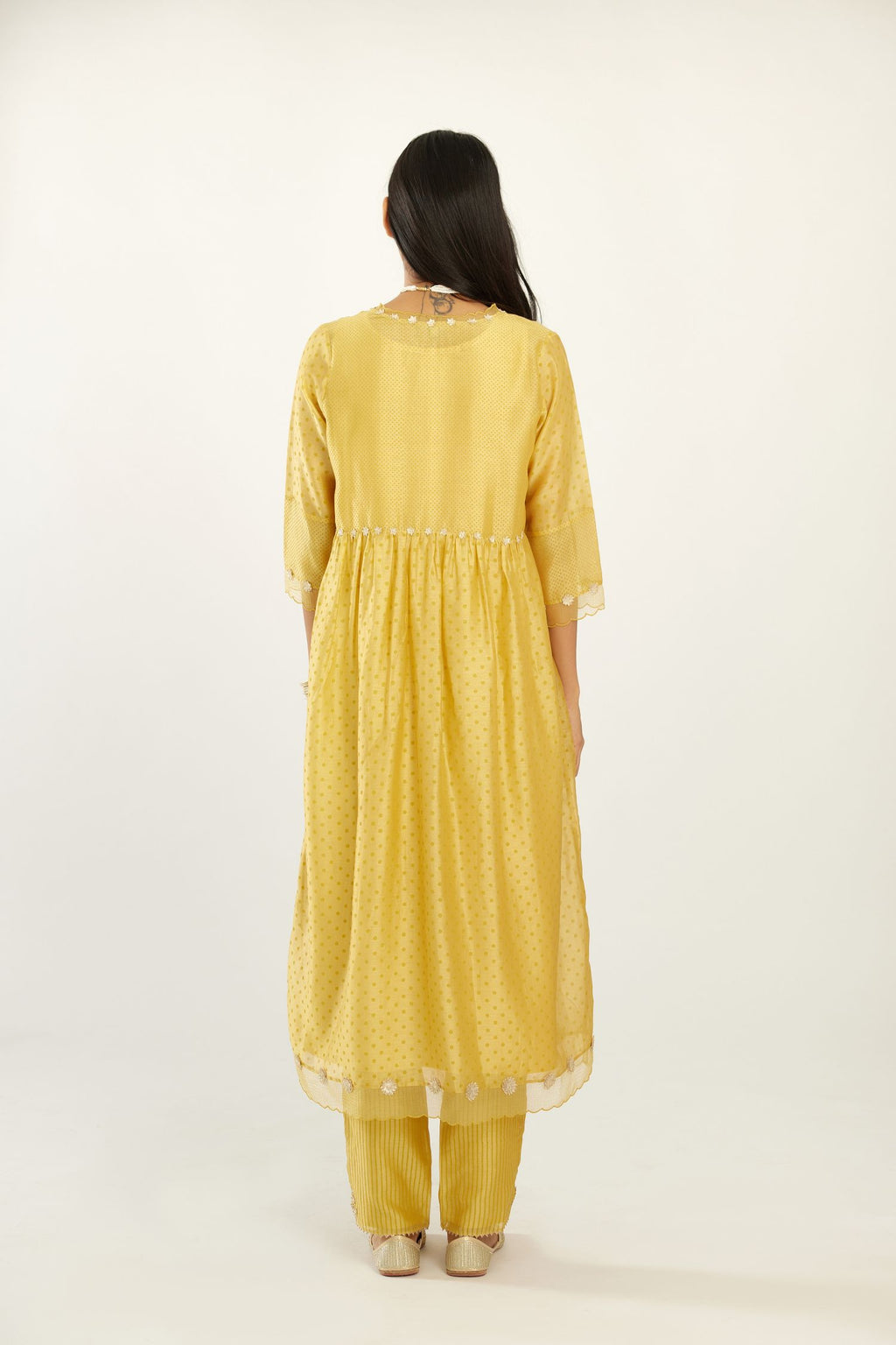 Yellow hand block printed V neck gathered kurta set, highlighted with gota flower embroidery and scalloped organza at edges.