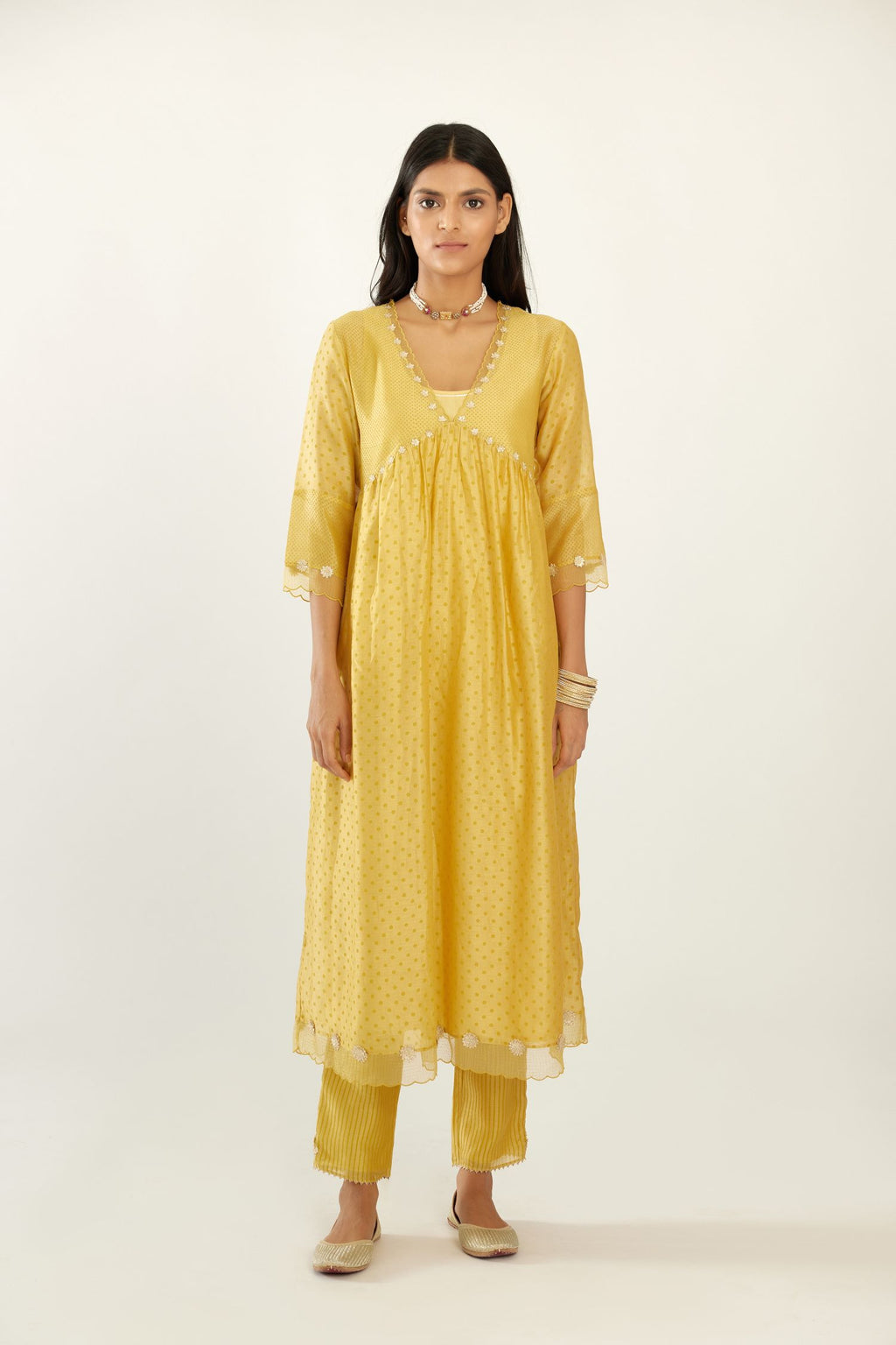 Yellow hand block printed V neck gathered kurta set, highlighted with gota flower embroidery and scalloped organza at edges.