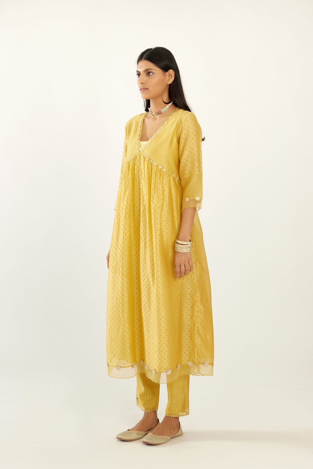 Yellow hand block printed V neck gathered kurta set, highlighted with gota flower embroidery and scalloped organza at edges.