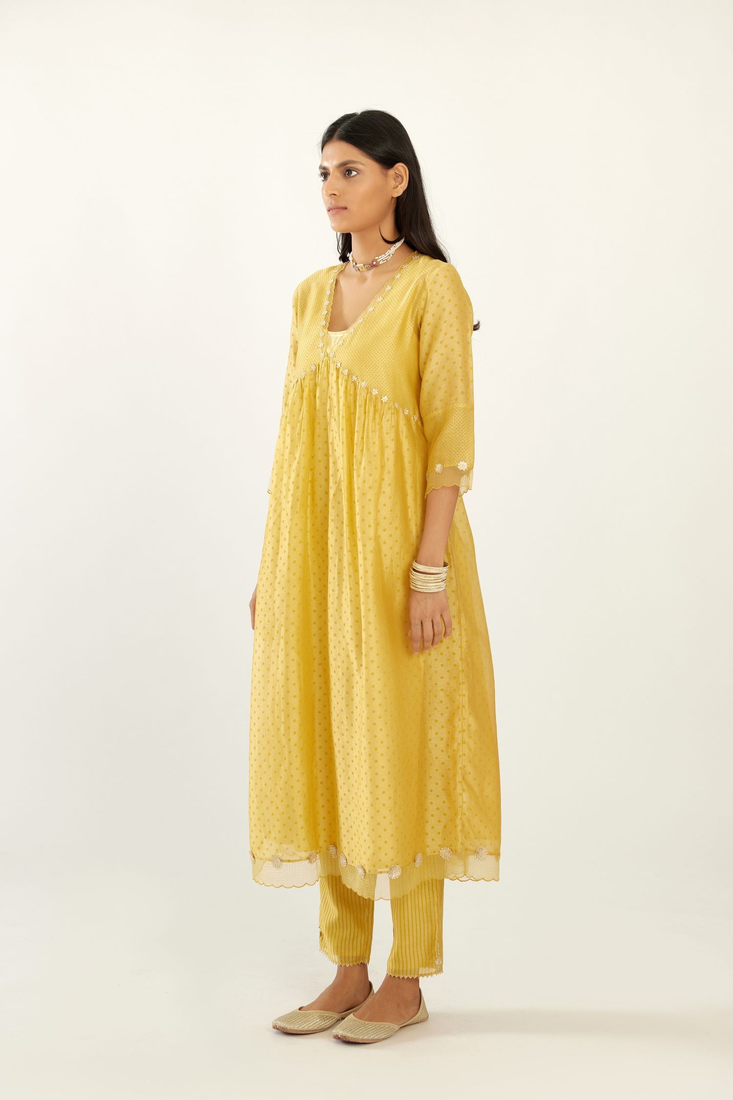 Yellow hand block printed V neck gathered kurta set, highlighted with gota flower embroidery and scalloped organza at edges.