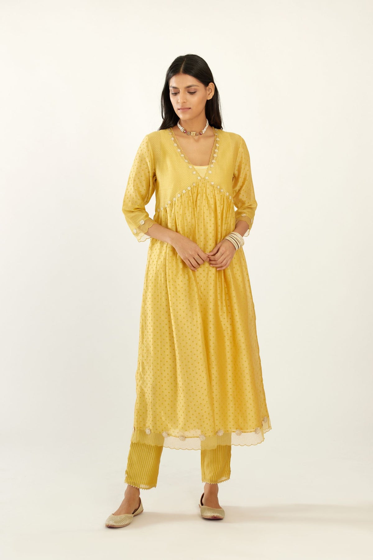 Yellow hand block printed V neck gathered kurta set, highlighted with gota flower embroidery and scalloped organza at edges.