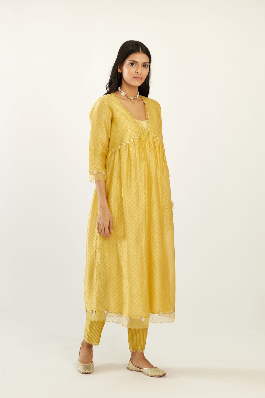 Yellow hand block printed V neck gathered kurta set, highlighted with gota flower embroidery and scalloped organza at edges.