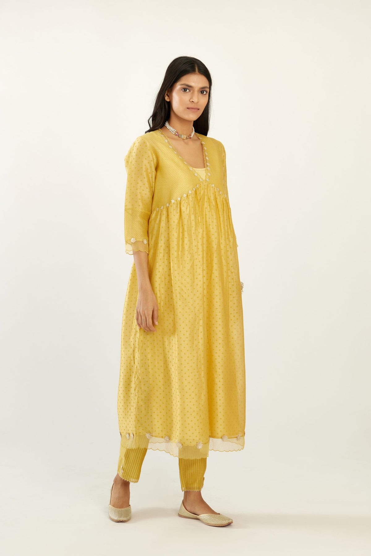 Yellow hand block printed V neck gathered kurta set, highlighted with gota flower embroidery and scalloped organza at edges.