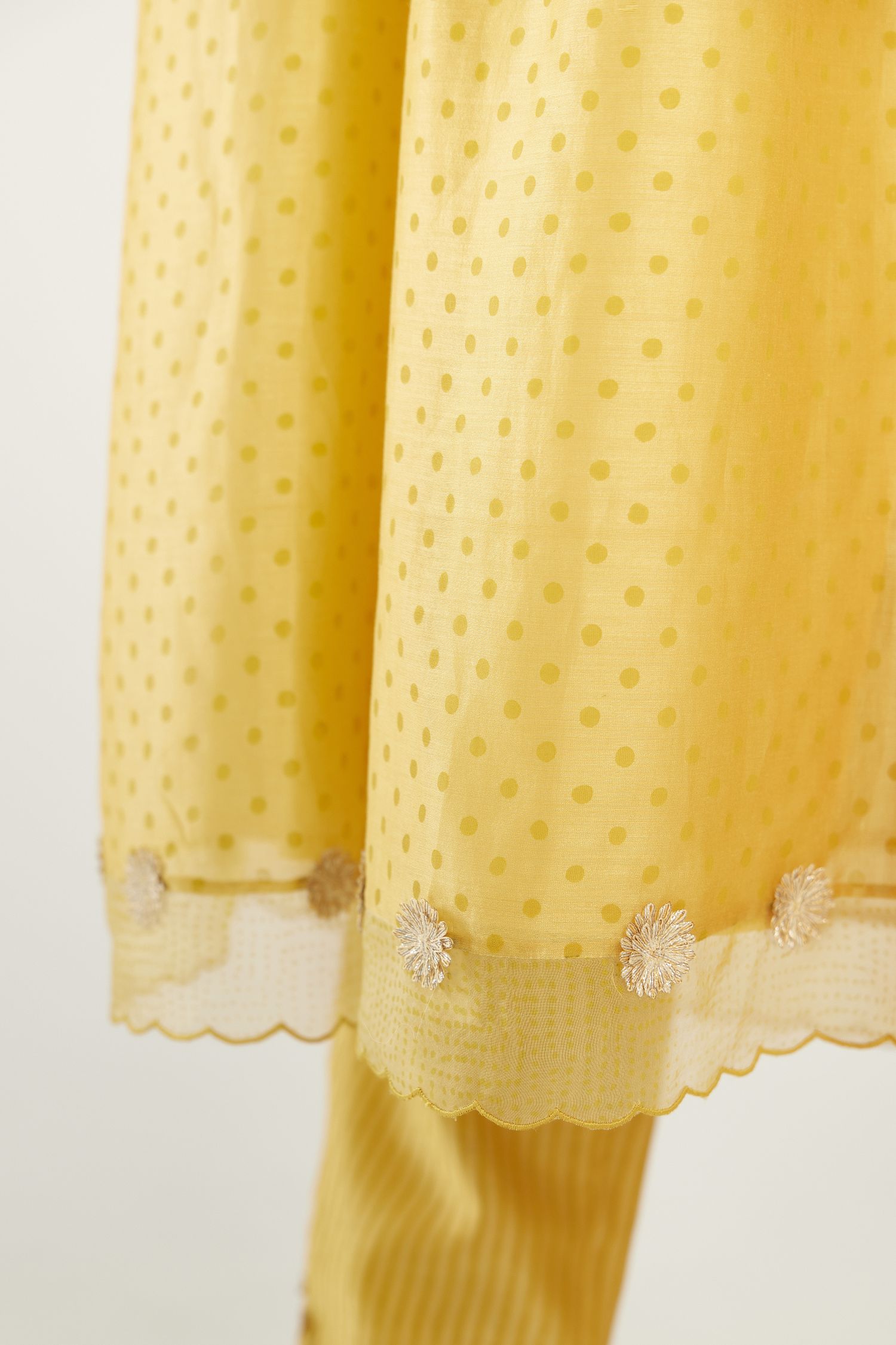 Yellow hand block printed V neck gathered kurta set, highlighted with gota flower embroidery and scalloped organza at edges.