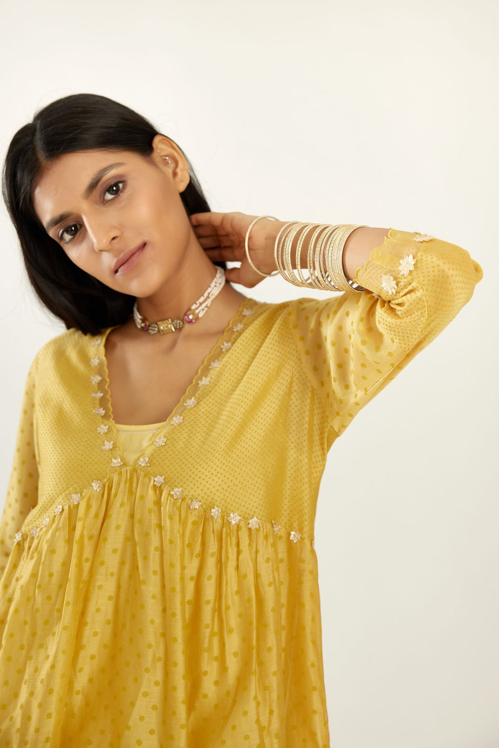 Yellow hand block printed V neck gathered kurta set, highlighted with gota flower embroidery and scalloped organza at edges.