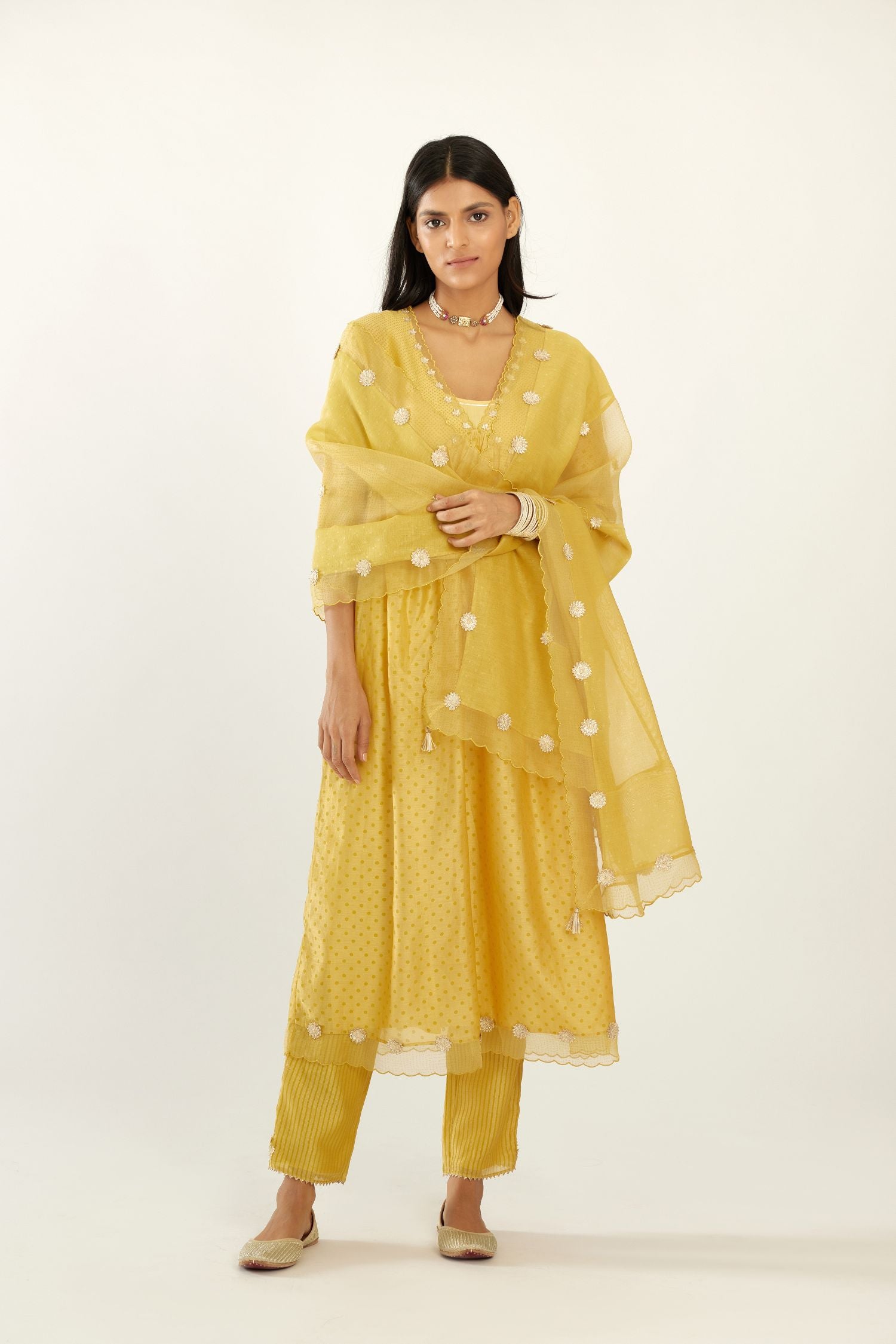Yellow hand block printed V neck gathered kurta set, highlighted with gota flower embroidery and scalloped organza at edges.