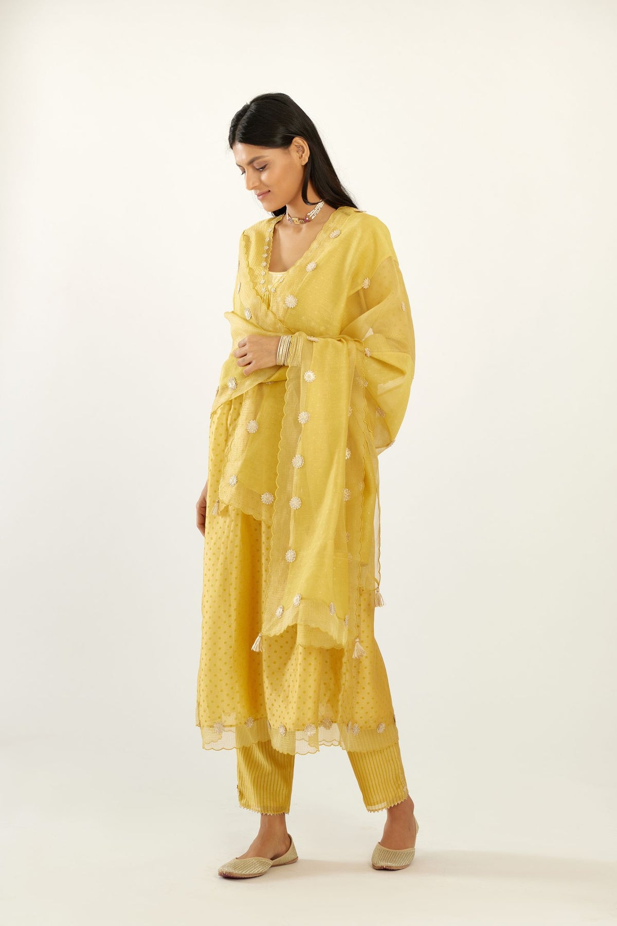 Yellow hand block printed V neck gathered kurta set, highlighted with gota flower embroidery and scalloped organza at edges.