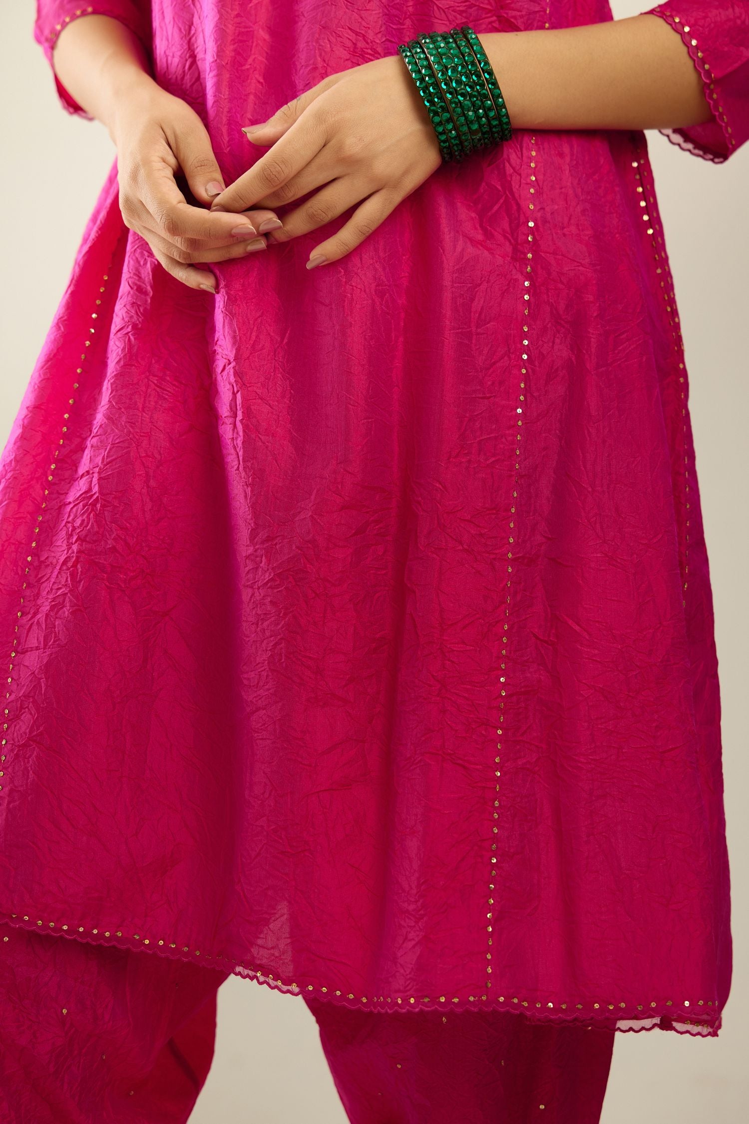 Silk hand crushed short kalidar kurta set with button placket, highlighted with gold sequins and embroidered scalloped organza at edges.