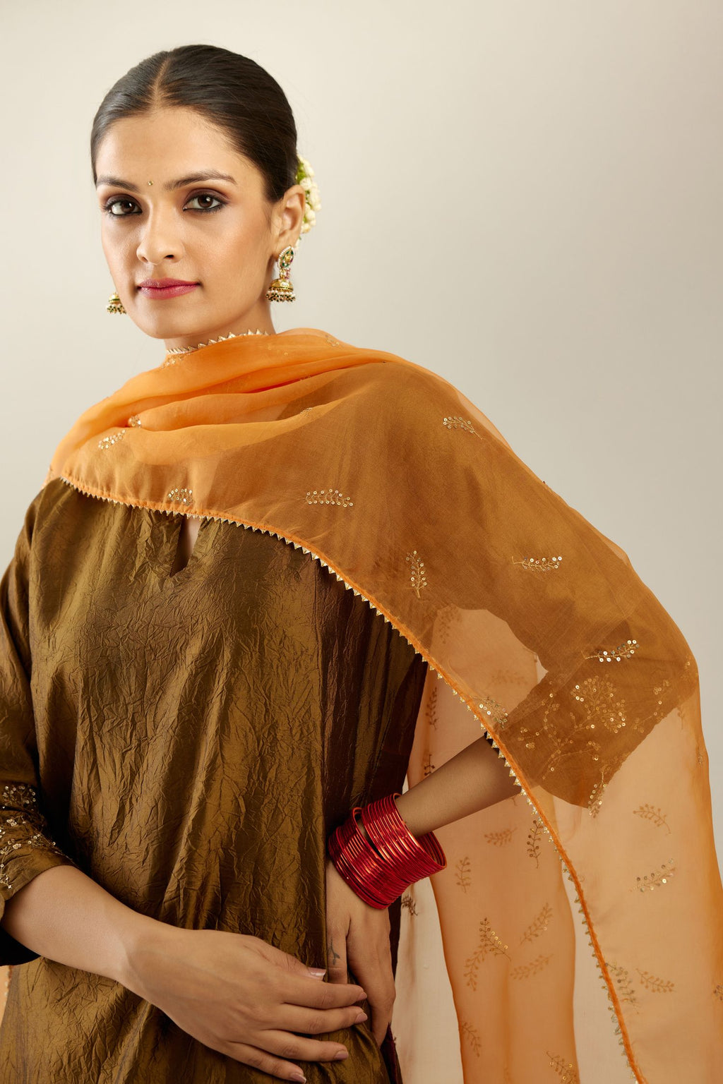 Orange silk organza dupatta with embroidered leaf clusters on all four corners of the dupatta and small leaf motif sprayed all over it.