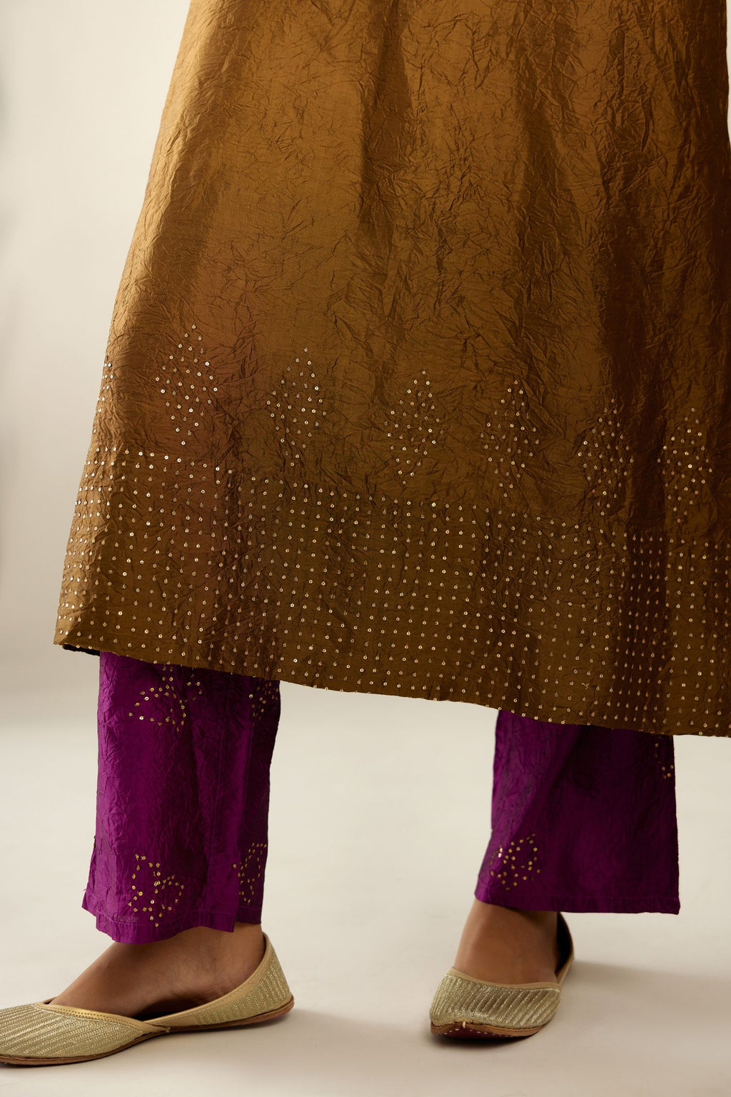 Golden olive silk hand crushed kurta set with concealed button placket neckline, highlighted with gold sequins heavy work at hem.