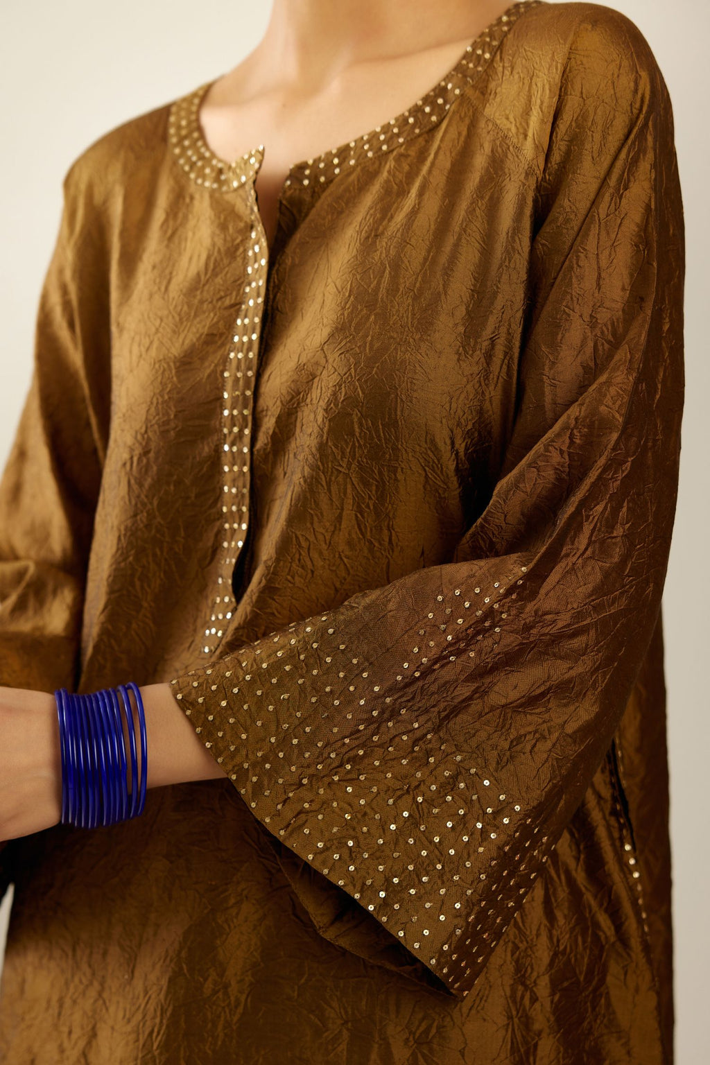 Golden olive silk hand crushed kurta set with concealed button placket neckline, highlighted with gold sequins heavy work at hem.