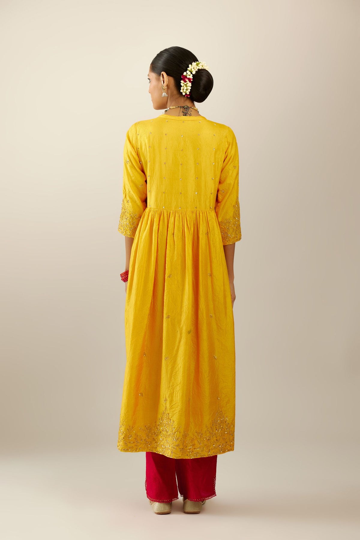 Yellow hand crushed silk kurta set with wavy empire waistline, gathers at waist and all-over gold sequins work detailing.