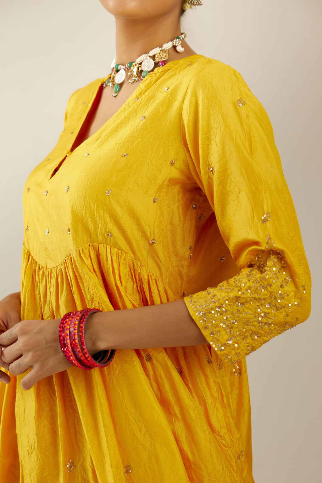 Yellow hand crushed silk kurta set with wavy empire waistline, gathers at waist and all-over gold sequins work detailing.