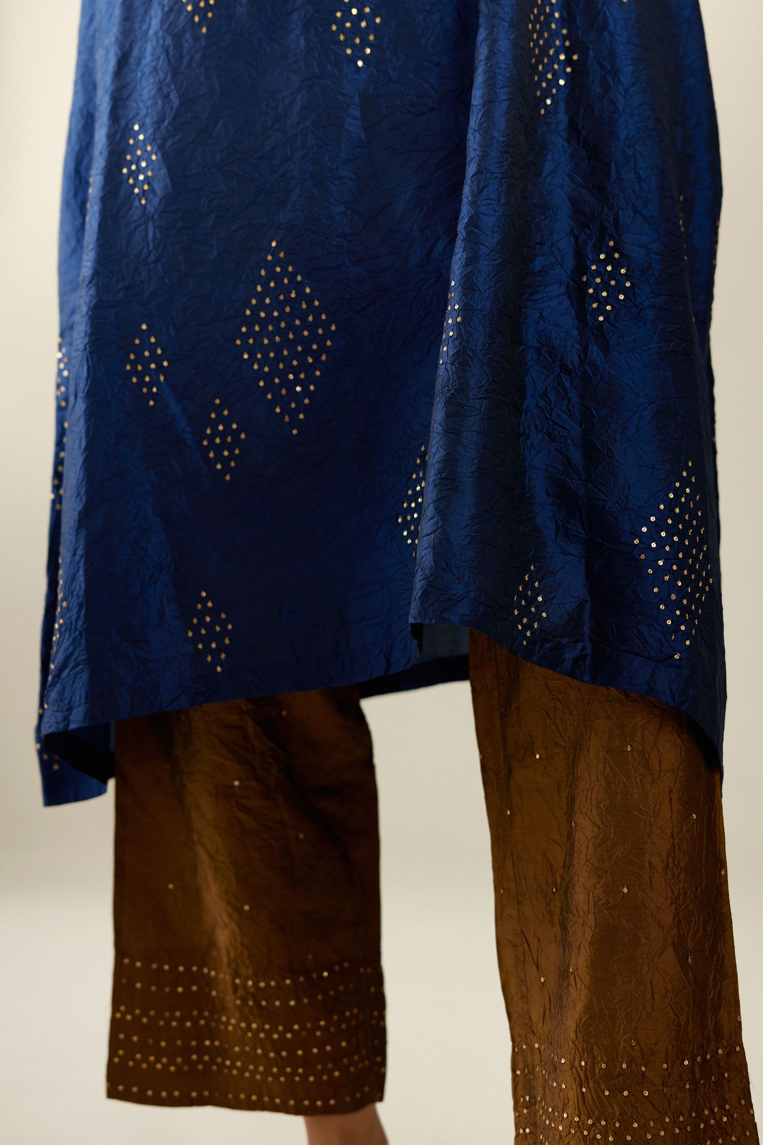 Navy blue silk hand crushed easy fit straight hem kurta, highlighted with all-over gold sequins in diamond shape, paired with golden olive hand crushed pure silk straight pants with gold sequins at hem in horizontal lines formation and side pockets.