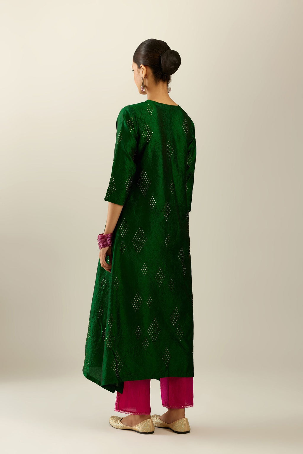 Dark green silk hand crushed A-line kurta with asymmetric hem, highlighted with all-over gold sequins diamonds, paired with raspberry  pants with scalloped and embroidered organza at edges and detailed with a single line of sequins at hem