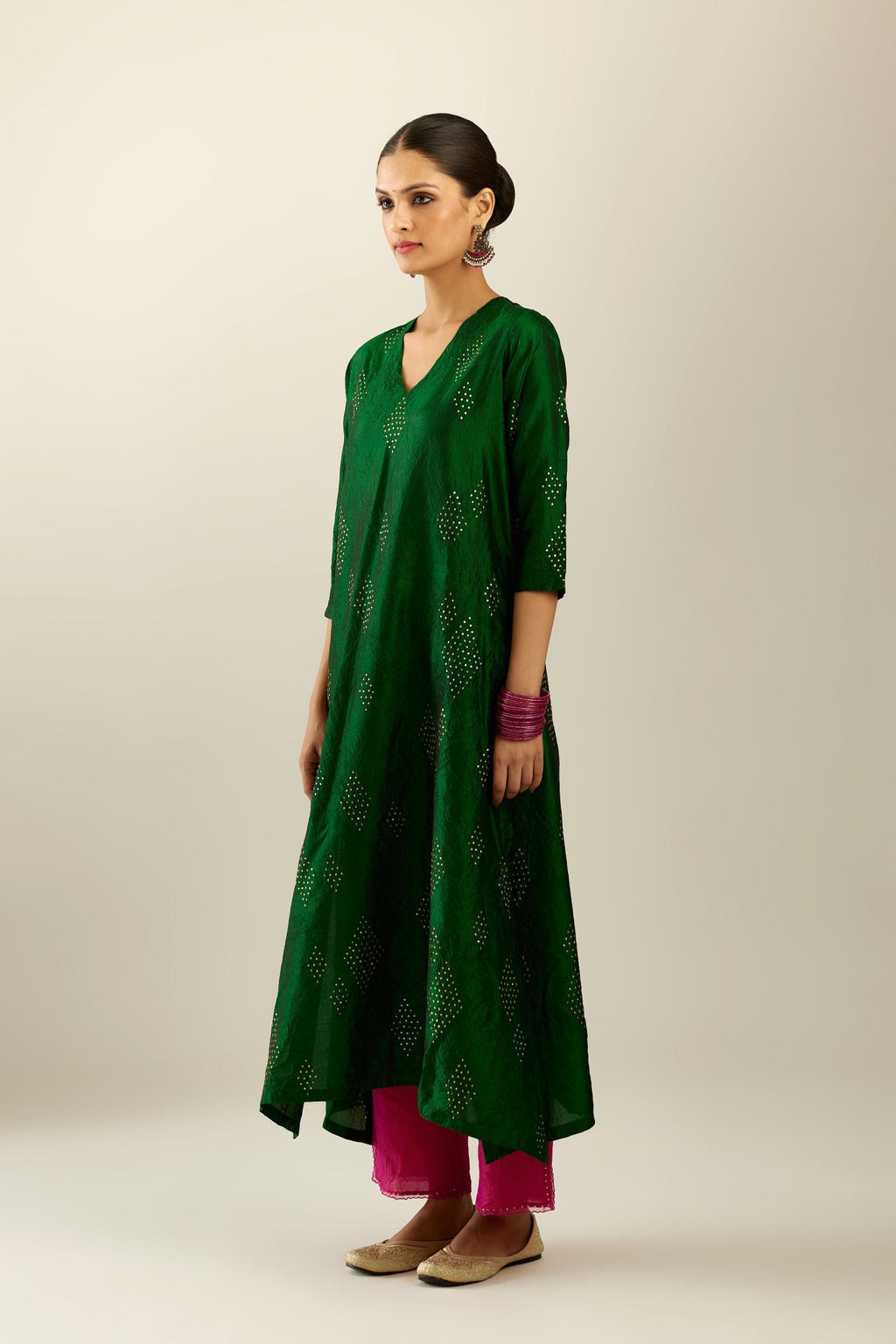 Dark green silk hand crushed A-line kurta with asymmetric hem, highlighted with all-over gold sequins diamonds, paired with raspberry  pants with scalloped and embroidered organza at edges and detailed with a single line of sequins at hem