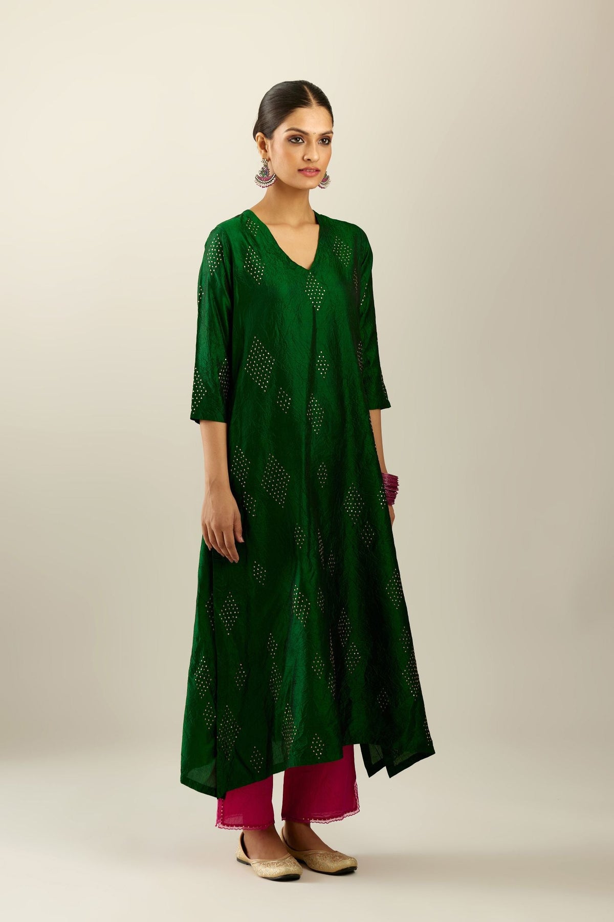 Dark green silk hand crushed A-line kurta with asymmetric hem, highlighted with all-over gold sequins diamonds, paired with raspberry  pants with scalloped and embroidered organza at edges and detailed with a single line of sequins at hem