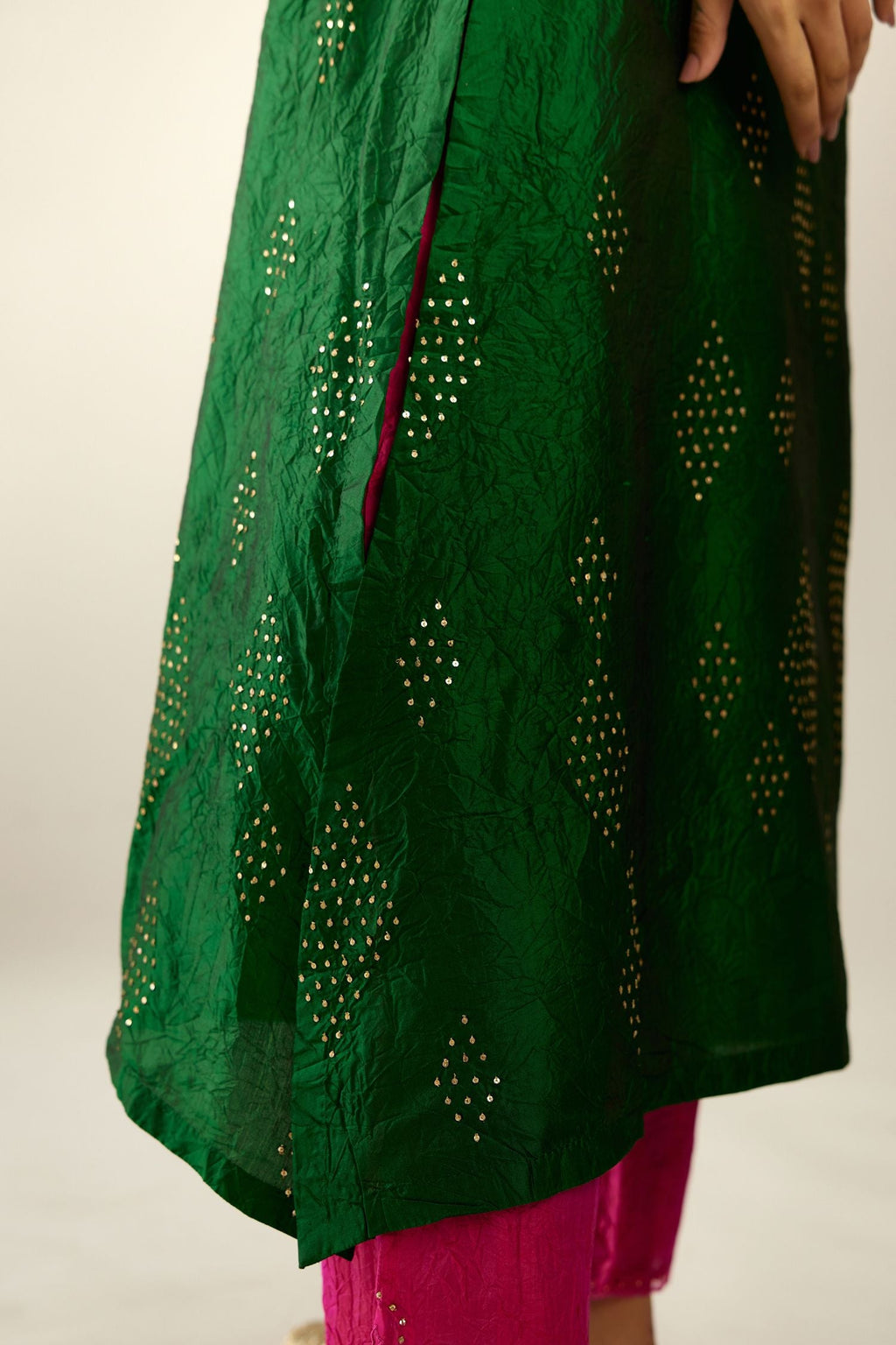 Dark green silk hand crushed A-line kurta with asymmetric hem, highlighted with all-over gold sequins diamonds, paired with raspberry  pants with scalloped and embroidered organza at edges and detailed with a single line of sequins at hem