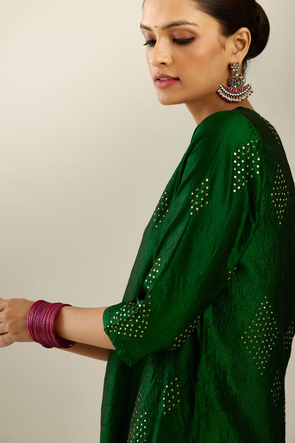 Dark green silk hand crushed A-line kurta with asymmetric hem, highlighted with all-over gold sequins diamonds, paired with raspberry  pants with scalloped and embroidered organza at edges and detailed with a single line of sequins at hem