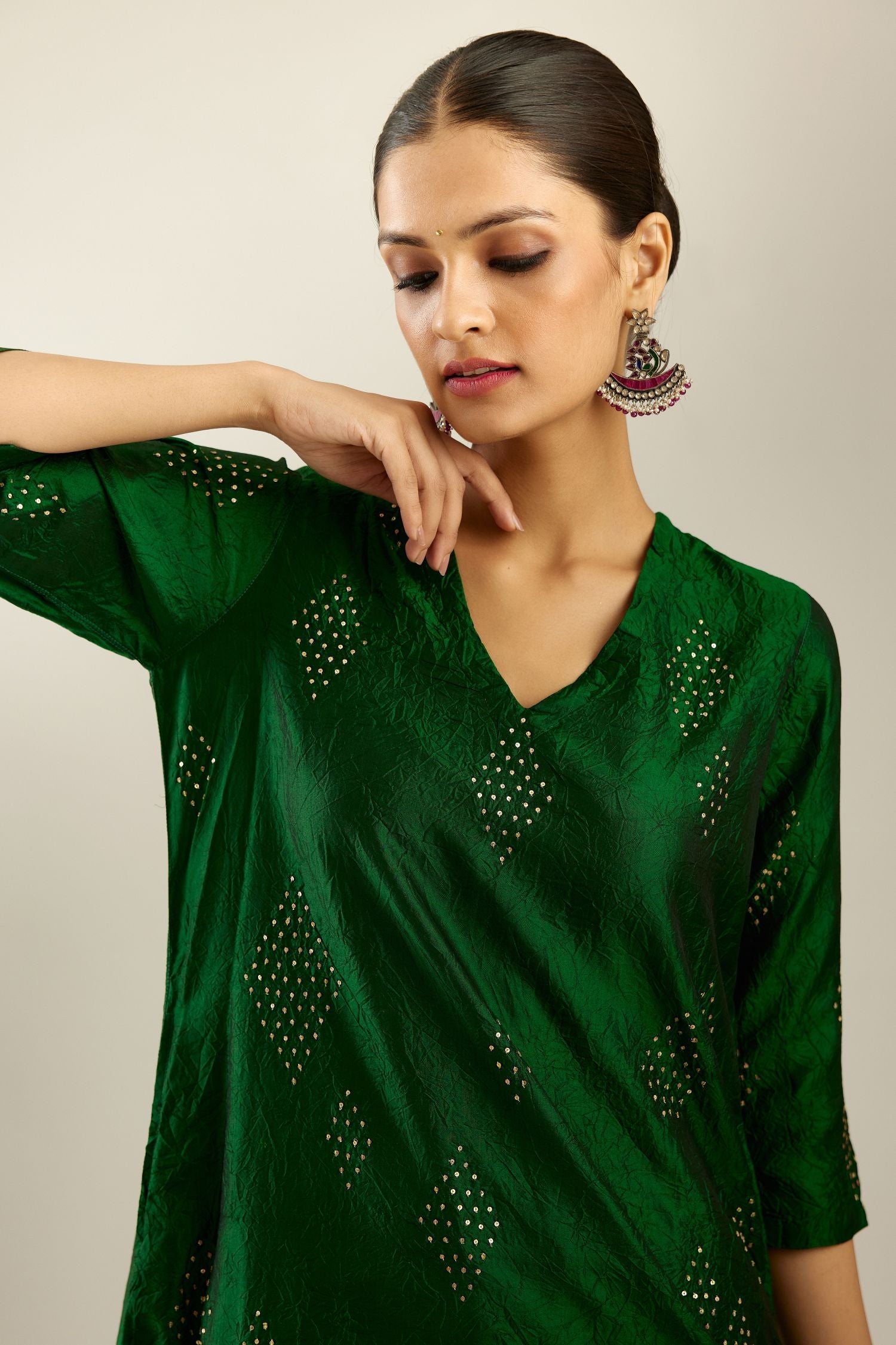 Dark green silk hand crushed A-line kurta with asymmetric hem, highlighted with all-over gold sequins diamonds, paired with raspberry  pants with scalloped and embroidered organza at edges and detailed with a single line of sequins at hem