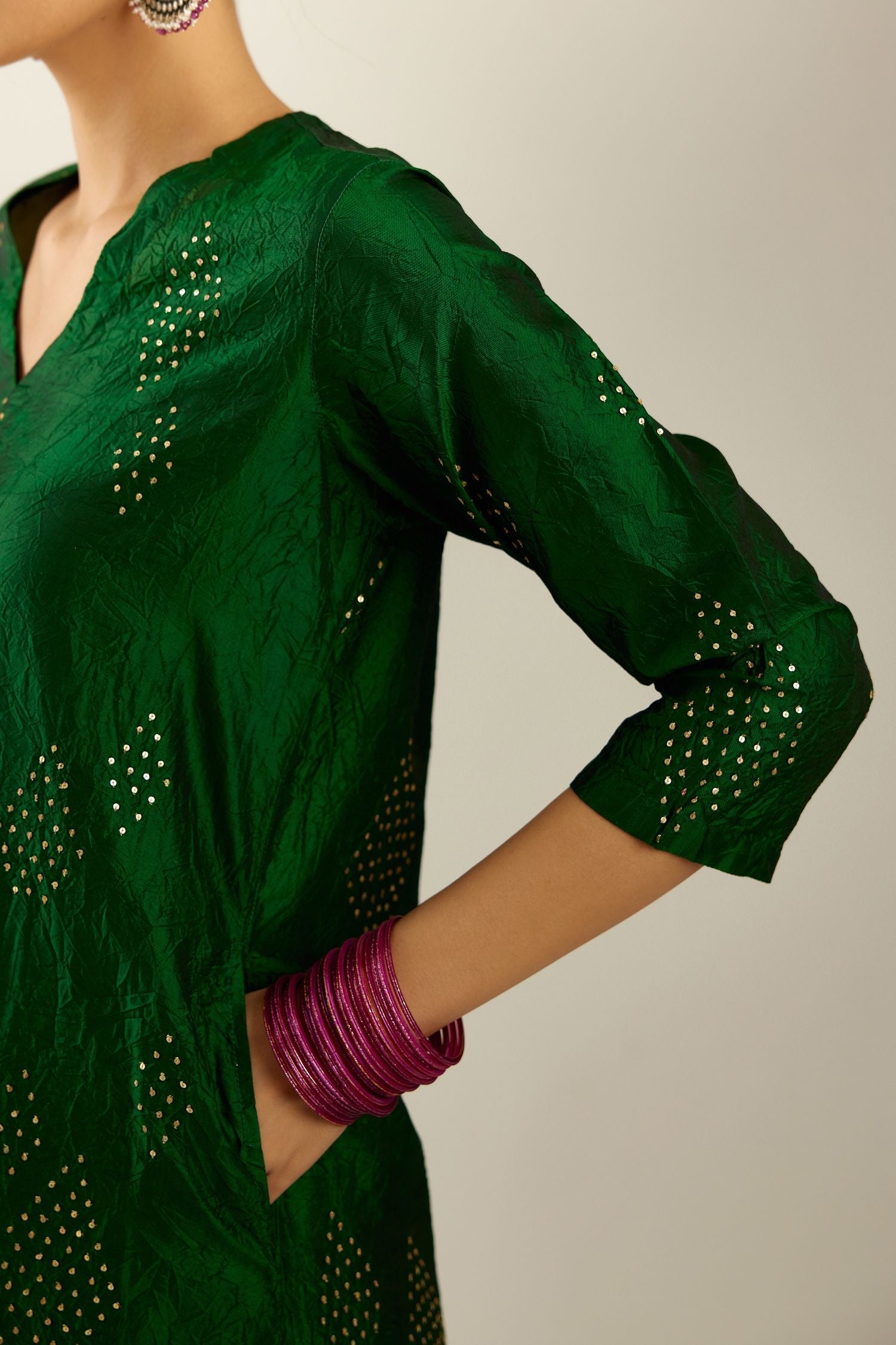 Dark green silk hand crushed A-line kurta with asymmetric hem, highlighted with all-over gold sequins diamonds, paired with raspberry  pants with scalloped and embroidered organza at edges and detailed with a single line of sequins at hem