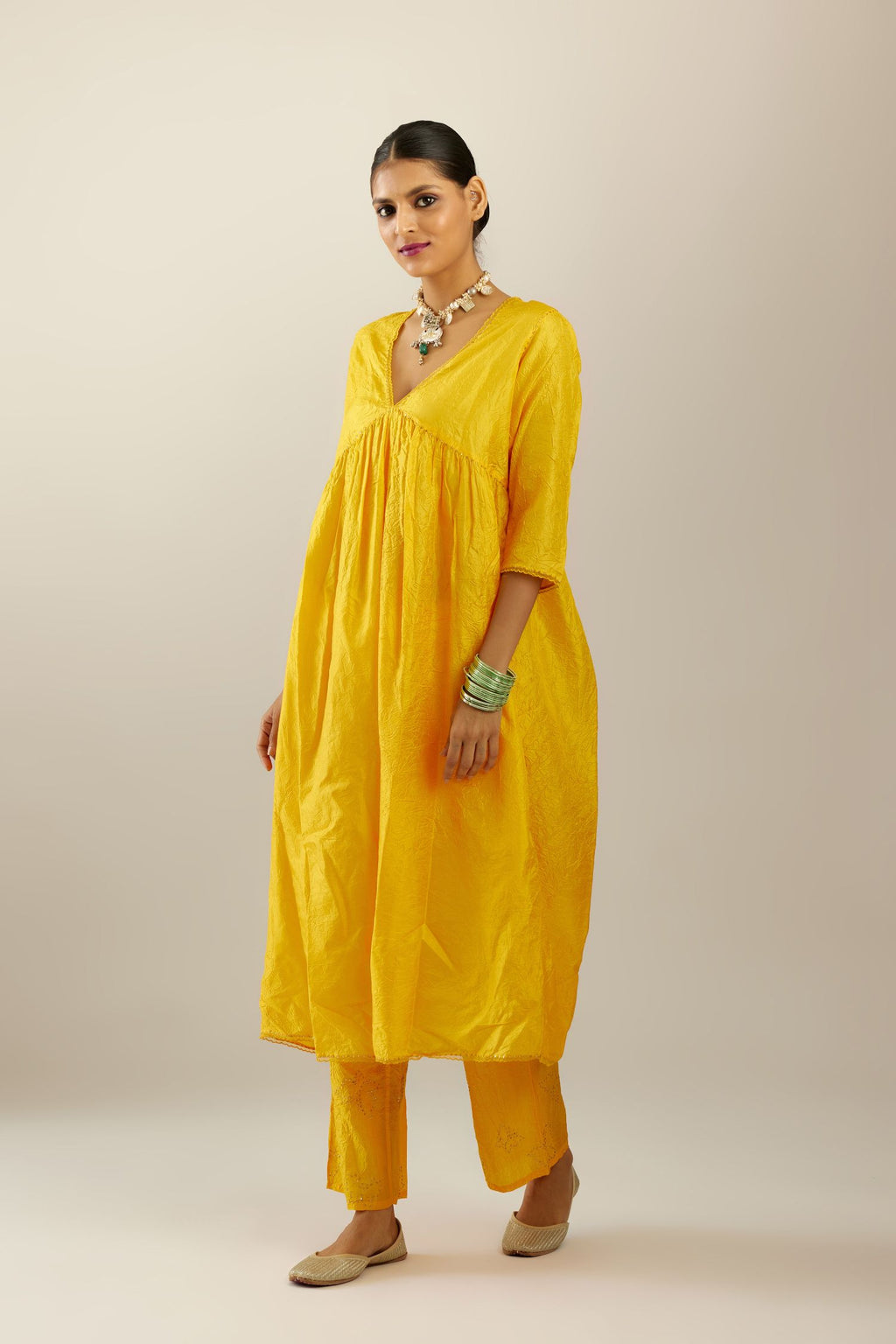 Deep yellow silk hand crushed V neck gathered kurta set, highlighted with gold sequins and embroidered scalloped organza at edges.