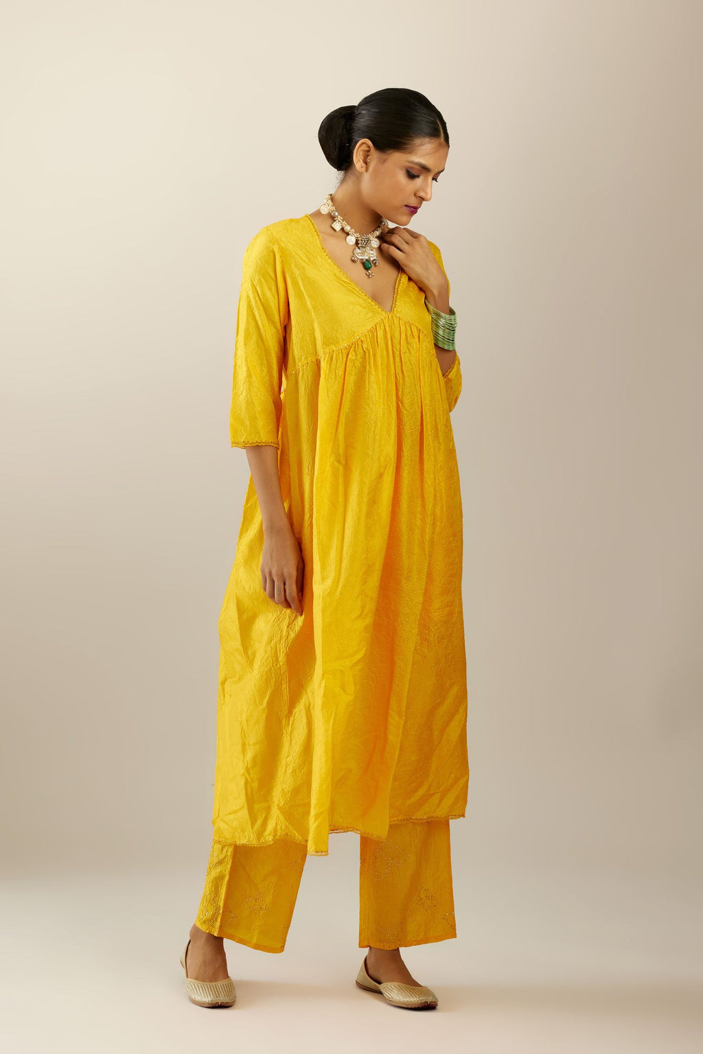 Deep yellow silk hand crushed V neck gathered kurta set, highlighted with gold sequins and embroidered scalloped organza at edges.