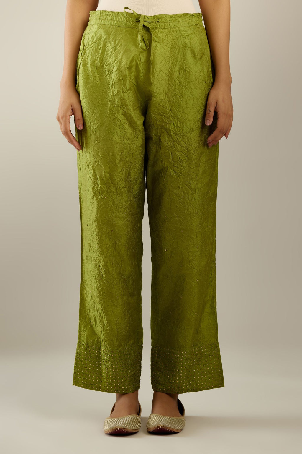 Apple green hand crushed silk straight pants detailed with gold sequins at hem and a single sequin buti is sprayed all over the pants and side pockets