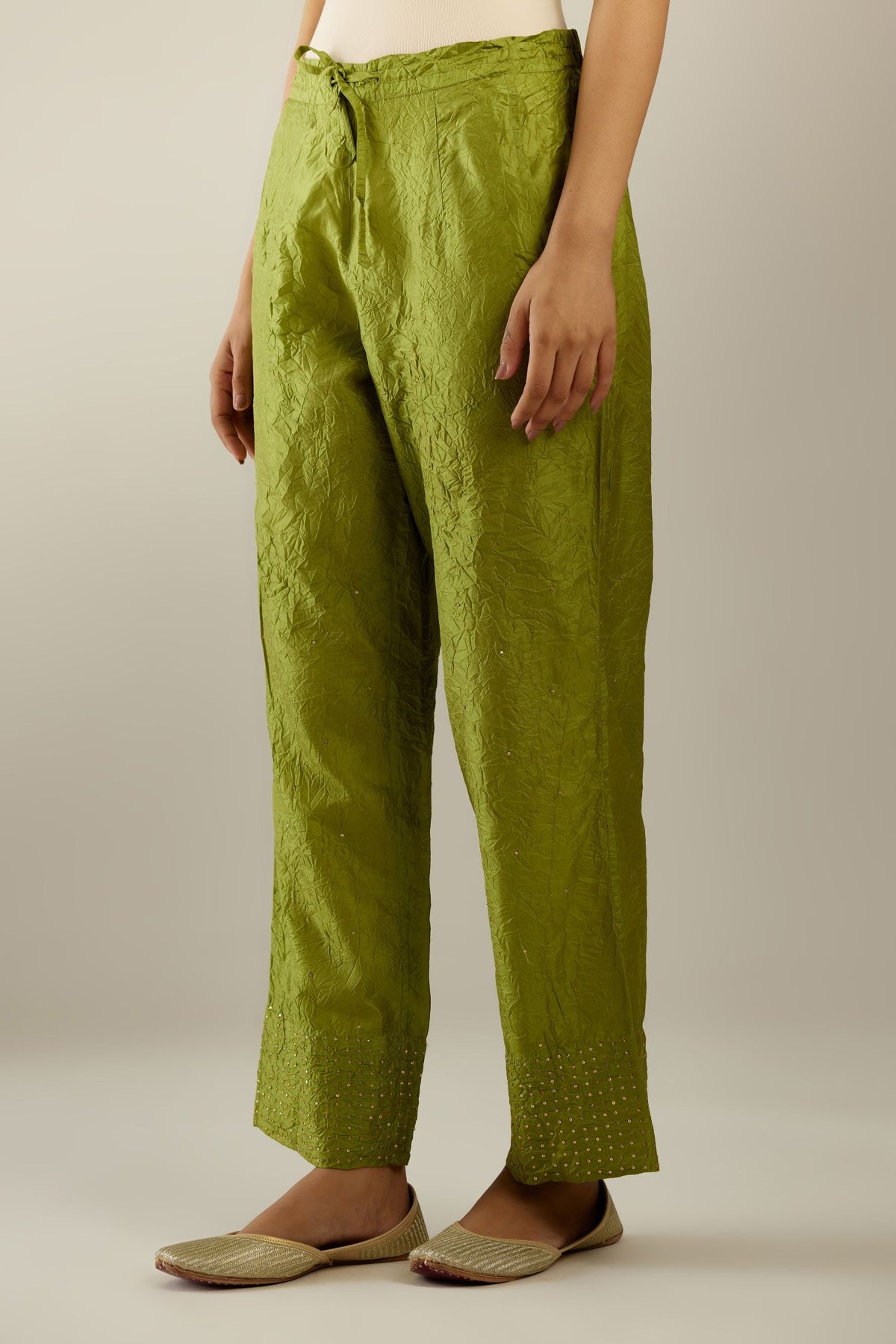 Apple green hand crushed silk straight pants detailed with gold sequins at hem and a single sequin buti is sprayed all over the pants and side pockets