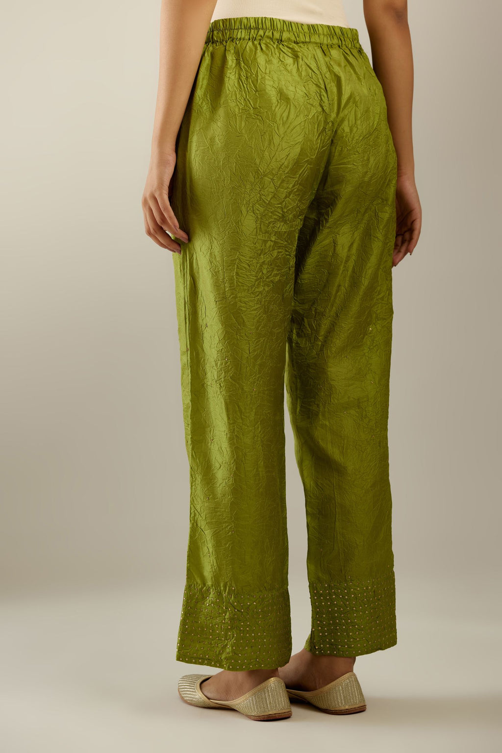 Apple green hand crushed silk straight pants detailed with gold sequins at hem and a single sequin buti is sprayed all over the pants and side pockets