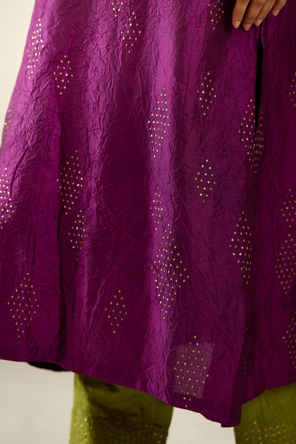 Sangria silk hand crushed A-line kurta set with asymmetric hem, highlighted with all-over gold sequins diamonds.