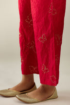 Red silk pants with side pockets and assorted sequined butterflies till mid-calf length.