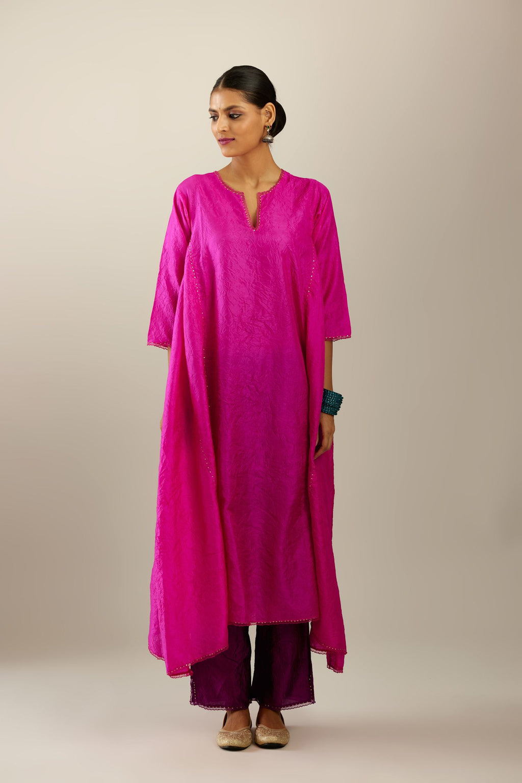 Fiji fuchsia hand crushed silk kurta set with asymmetric hem, highlighted with gold sequins and embroidered scalloped organza at edges.