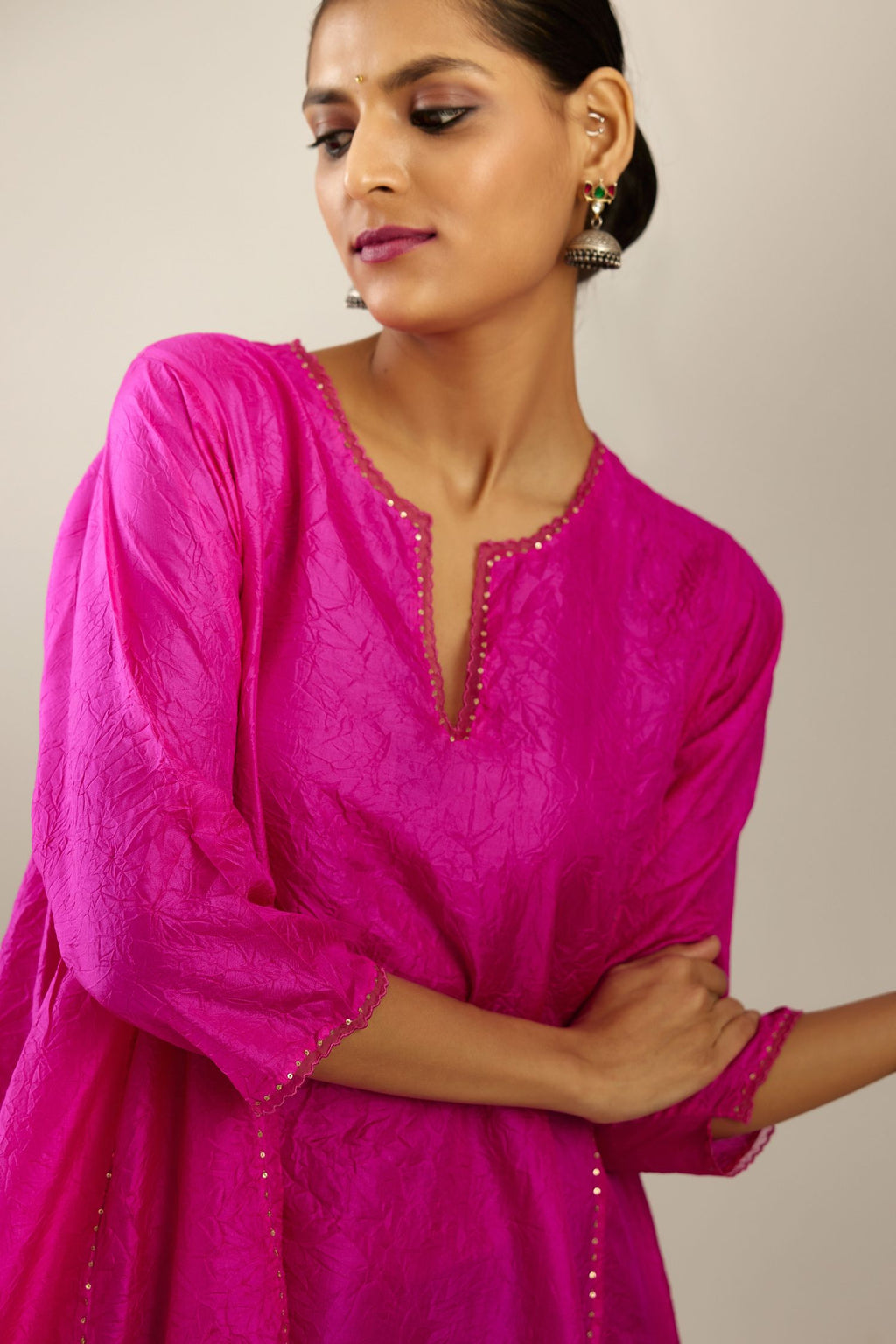 Fiji fuchsia hand crushed silk kurta set with asymmetric hem, highlighted with gold sequins and embroidered scalloped organza at edges.