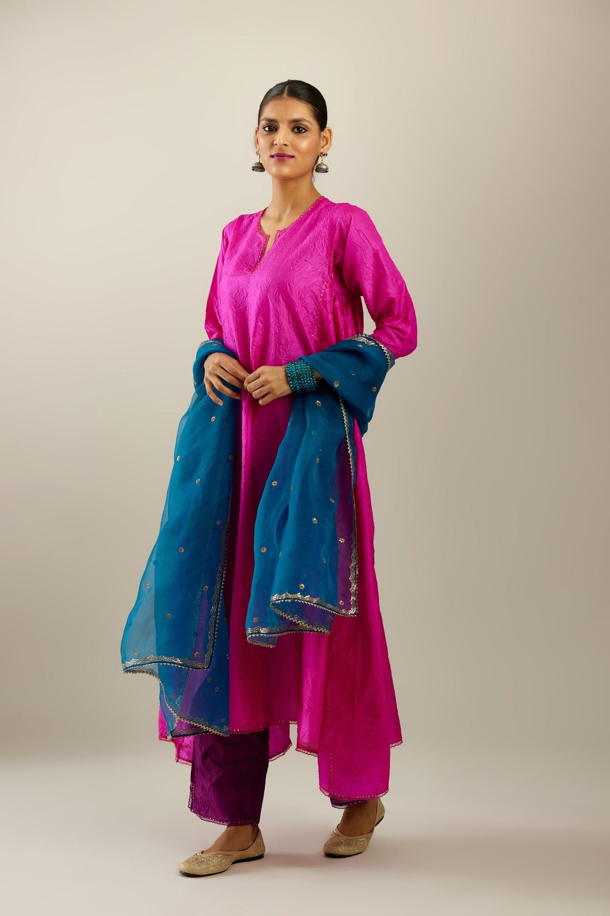 Fiji fuchsia hand crushed silk kurta set with asymmetric hem, highlighted with gold sequins and embroidered scalloped organza at edges.