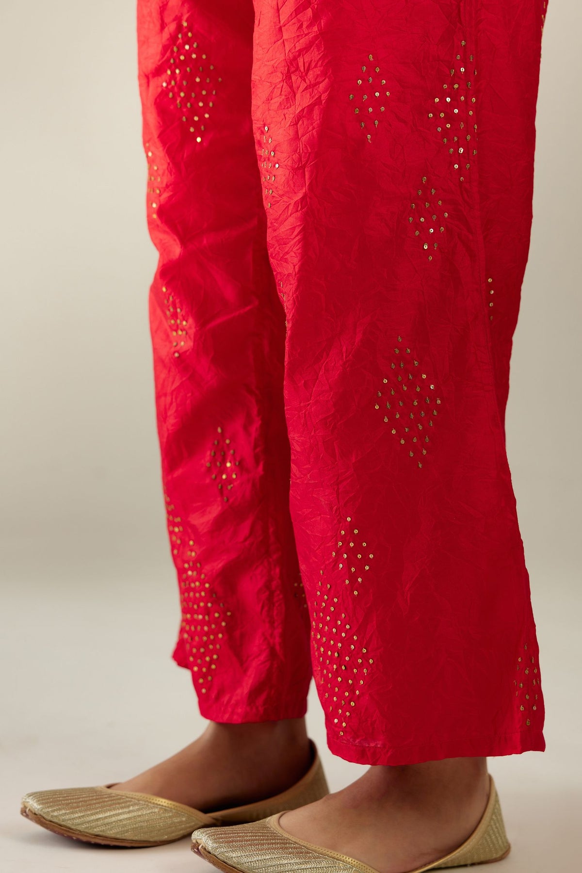 Red hand crushed pure silk straight pants with assorted diamond shape golden sequins work till knee length and side pockets.